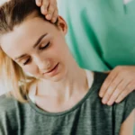 Crop professional male massage therapist in green medical uniform doing therapeutic neck massage on content female patient wearing casual clothes