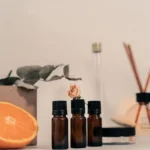 Elegant still life featuring aromatherapy bottles, orange slice, and dried flowers.